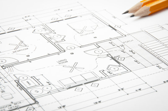 Construction blueprints on the worktable and yellow pencils