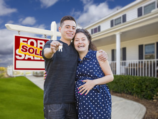 Hispanic Couple with Keys In Front of Home and Sign