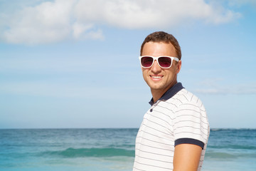 Man standing with white sunglasses on summer sea coast