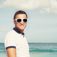 Young man standing with sunglasses on sea coast
