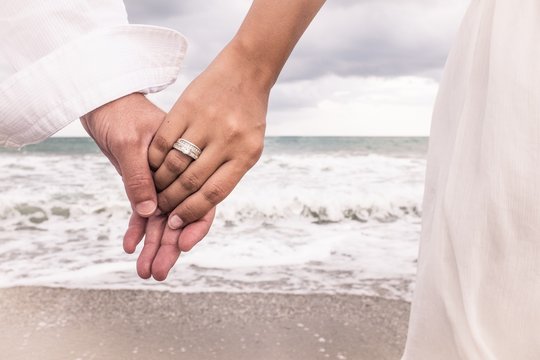 Hands with ring on the beach