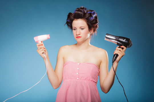 girl with curlers in hair holds hairdreyers