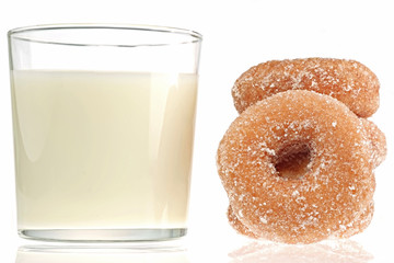 Glass of milk with donuts on white background