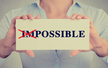woman hands card crossed off first two letters word impossible