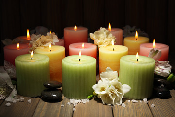 Beautiful candles with flowers on wooden background