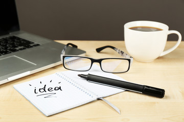 Cup of coffee with note Idea in notebook and glasses