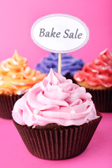 Delicious cupcakes with inscription on color background