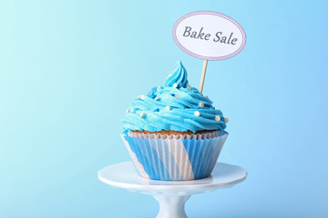 Delicious cupcake with inscription on blue background