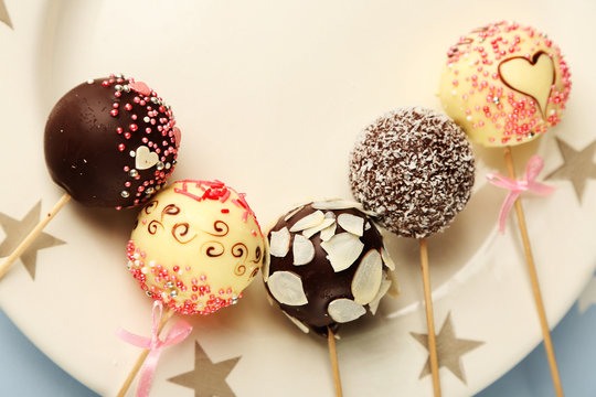 Tasty cake pops on plate, close up