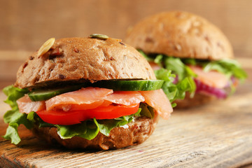 Sandwiches with salmon on cutting board, on wooden background