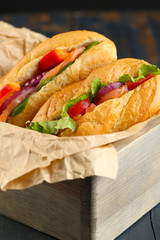 Sandwiches with salmon in wooden box on dark wooden background