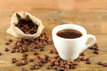 Cup of coffee with beans on rustic wooden background