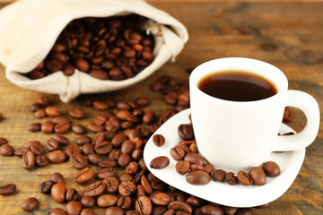 Cup of coffee with beans on rustic wooden background