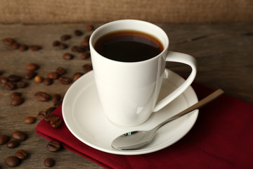 Cup of coffee with beans on rustic wooden background