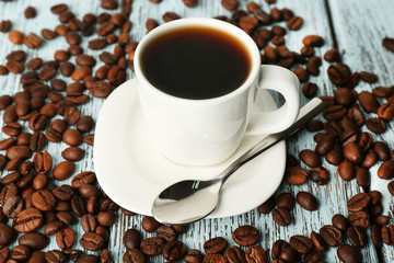Cup of coffee with beans on color rustic wooden background
