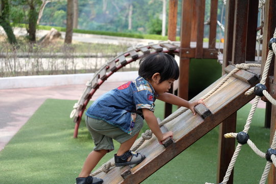 Boy climps a stair with rope at playground outdoor