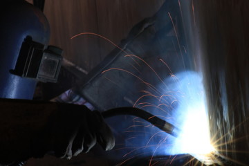 Industrial arc welder working in factory