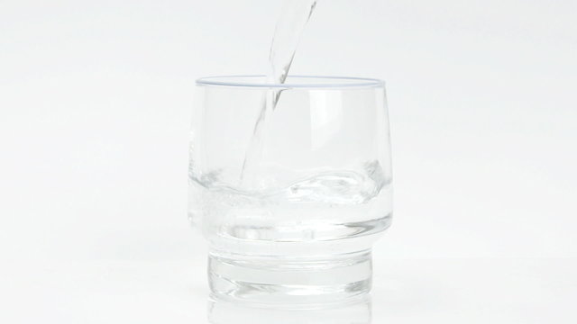 Transparent water liquid poured in glass on white background