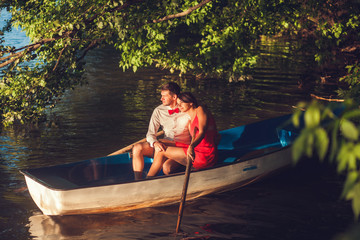 romantic couple sitting in the boat and admiring the sunset