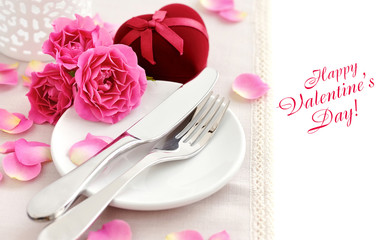 Romantic table setting with pink roses on a linen napkin