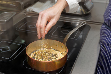 Chef is pouring fregola pasta in pan