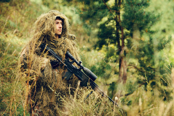 sniper soldier stands with arms and looking at the target