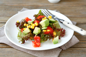 nutritious salad with avocado, tomatoes and corn on a plate