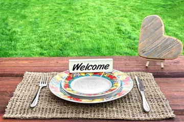 Tuinposter Picnic Table with Wooden Heart and Sign Welcome © Alex