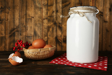 Milk can with eggs and eggshell on rustic wooden background