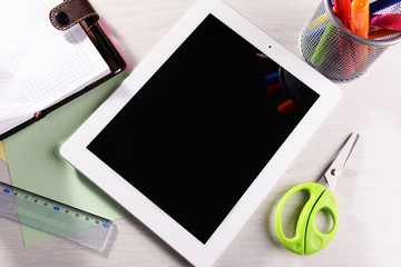 Tablet PC with office supplies on desktop background