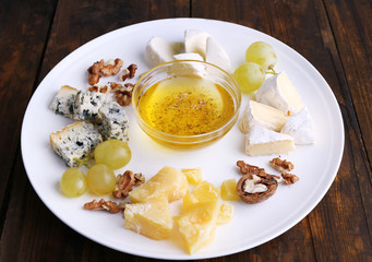 Different sort of cheese with grape, nuts and saucer