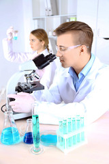 Young female and male scientists  with microscope in laboratory