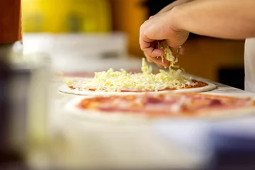 Foto auf Glas Nahaufnahme des Küchenchefs in weißer Uniform, der Pizza in der Küche macht © alexstreinu