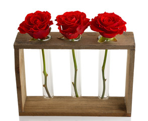Three fresh roses in glass vases and wooden stand isolated