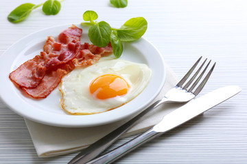 Bacon and eggs on color wooden table background
