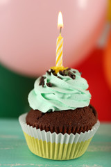 Delicious birthday cupcake on table on bright background