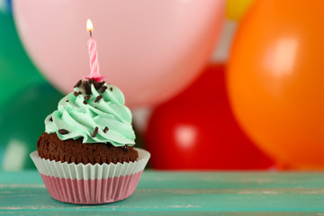 Delicious birthday cupcake on table on bright background