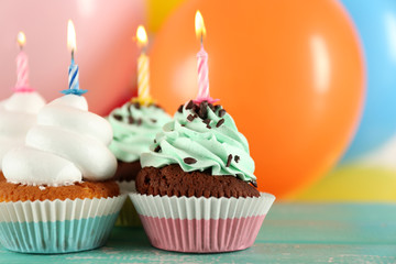 Delicious birthday cupcakes on table on bright background