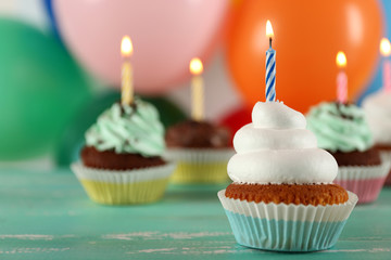Delicious birthday cupcakes on table on bright background
