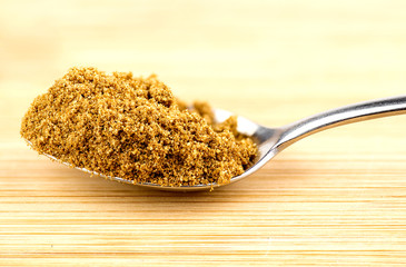 Macro closeup of crushed cumin seeds in spoonful