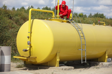 technician in red uniform working on large fuel tank