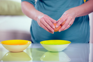 Female hands separating yolk and white of a cracked egg