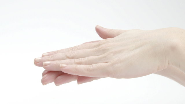 Young woman smearing body lotion on hands on white background