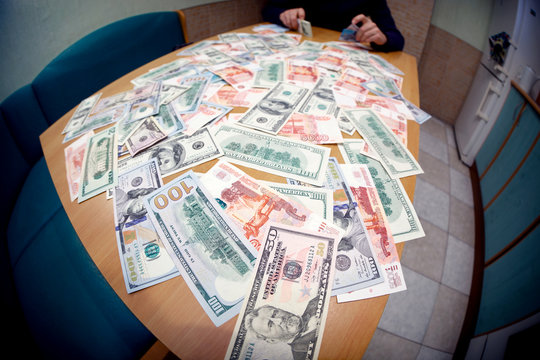 Urecognizable man counts money on kitchen table