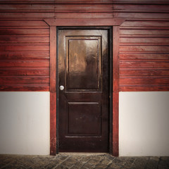 Old wooden door in white and red rural facade