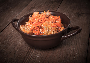 Fish marinated with carrots in a brown ceramic bowl on old woode