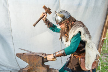 Fototapeta na wymiar Strong viking is repairing his sword