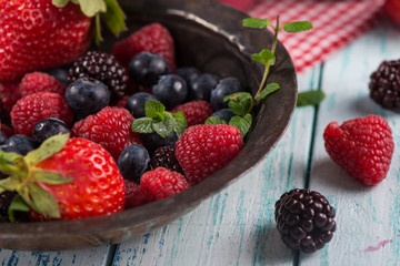 Fresh summer berries fruits in vintage bowl on rustic table