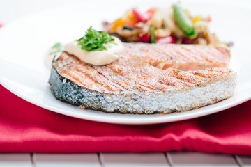 Grilled Salmon with Fresh vegetables on red background
