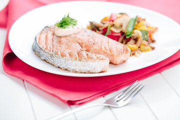Grilled Salmon with Fresh vegetables on red background